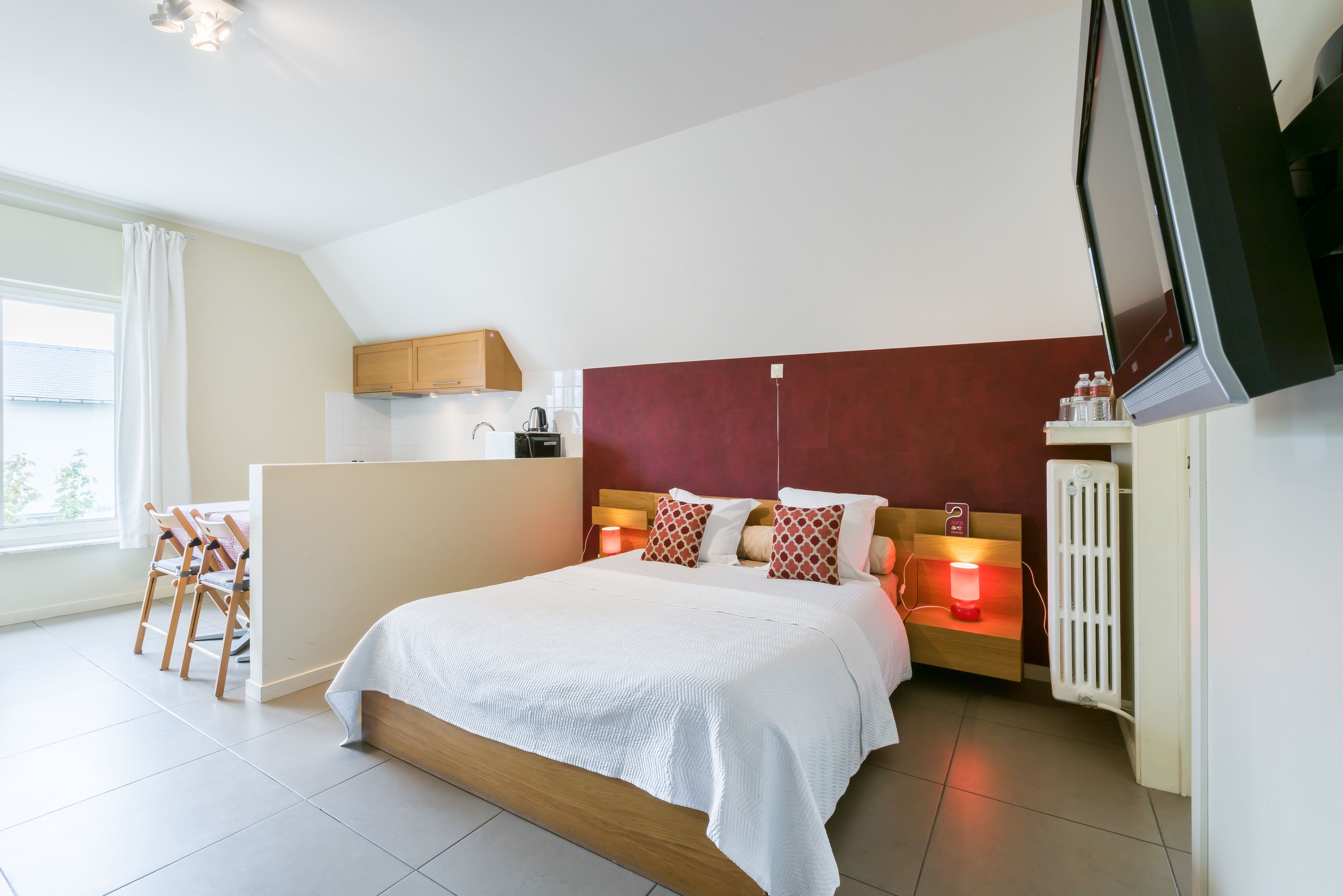 A bedroom with a large bed, a TV, a desk, and a chair.