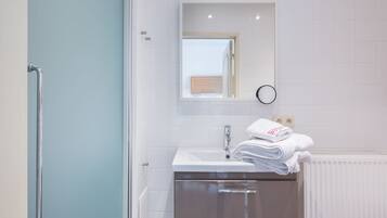 Een badkamer met een witte wastafel, een spiegel en een handdoekhouder.