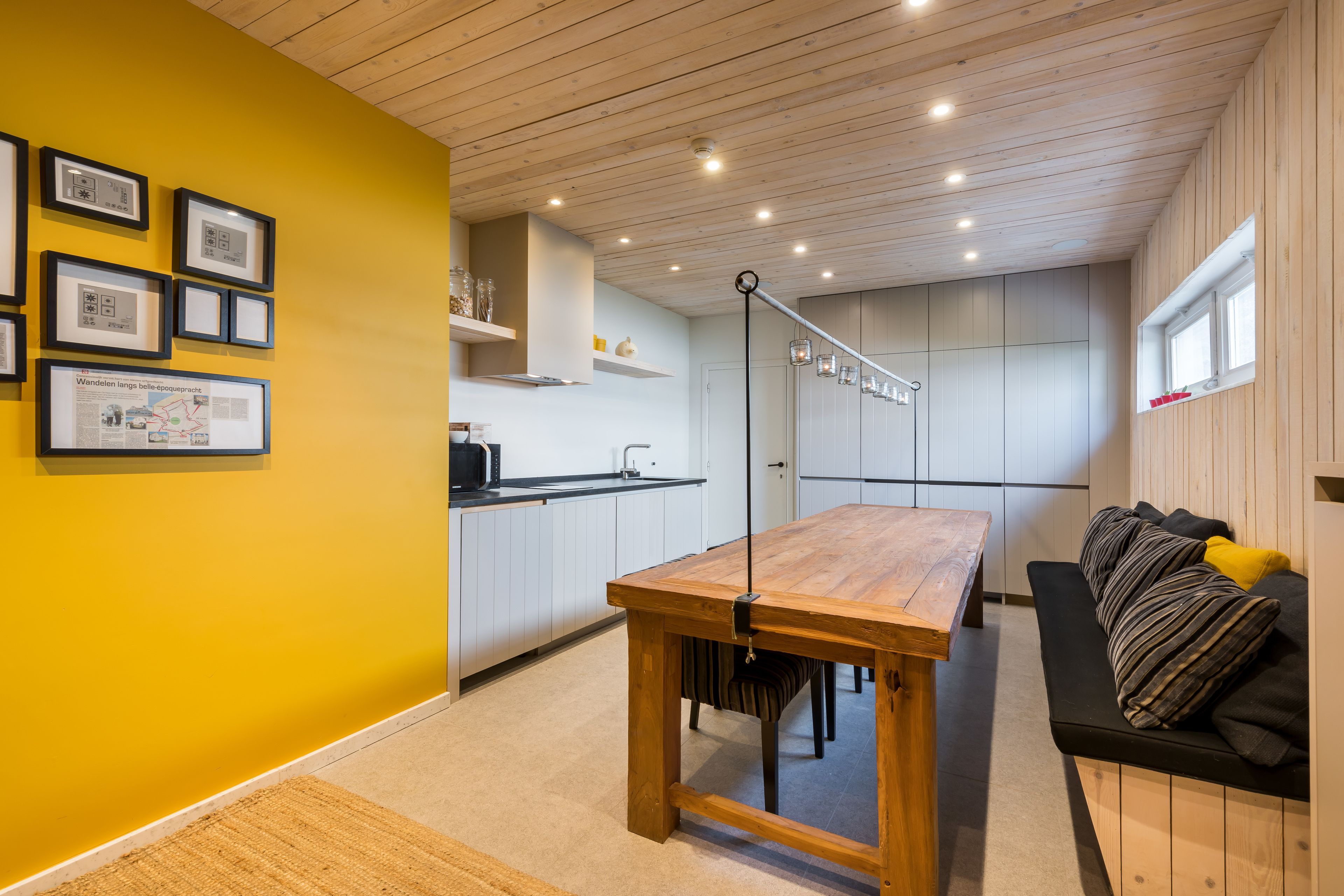 A modern kitchen with wooden cabinets, a dining table, and a bench.