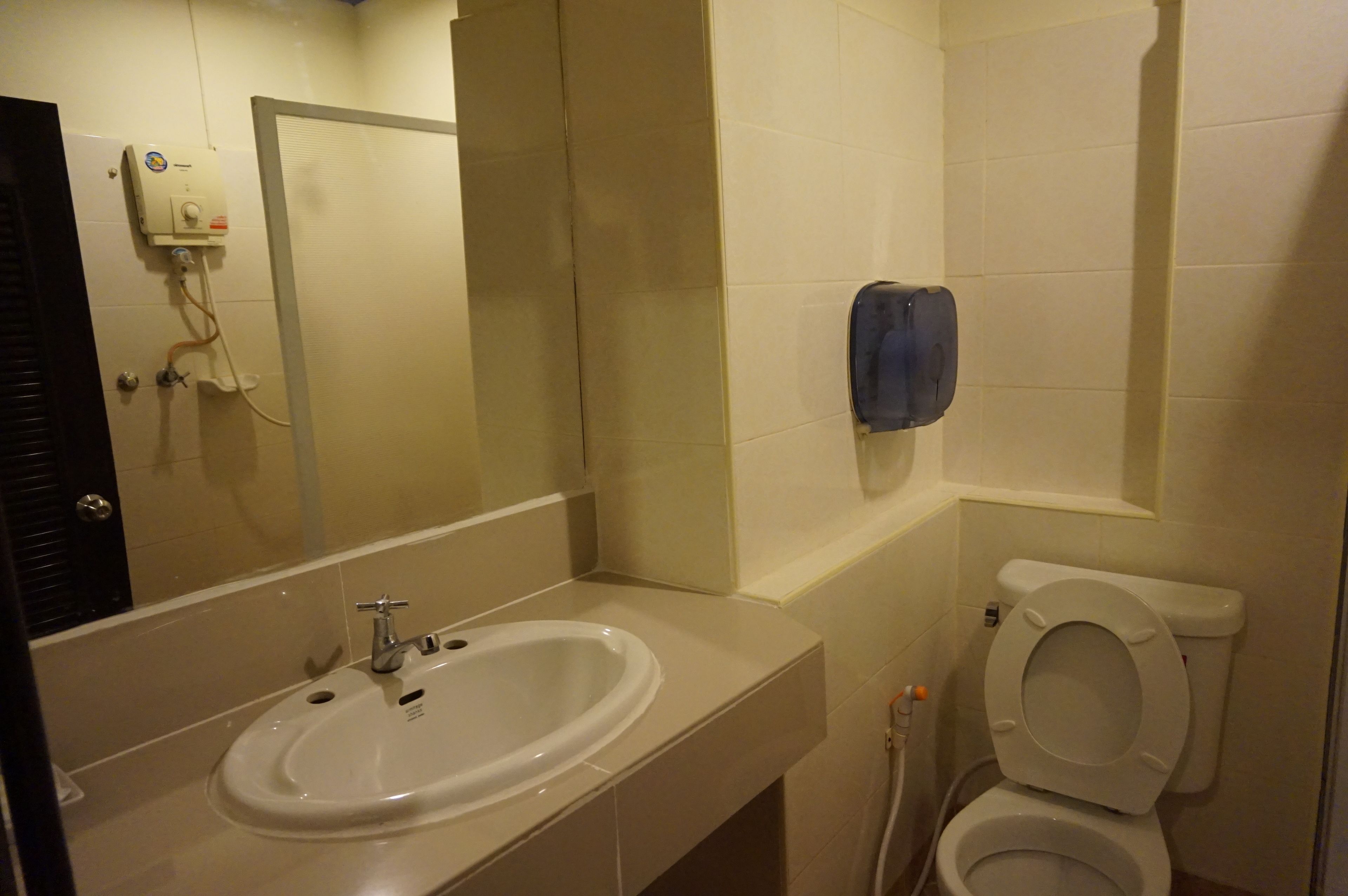 A bathroom with a sink, toilet, and hand dryer.
