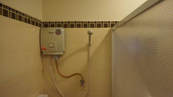 Un baño con ducha empotrada, inodoro y paredes con azulejos.