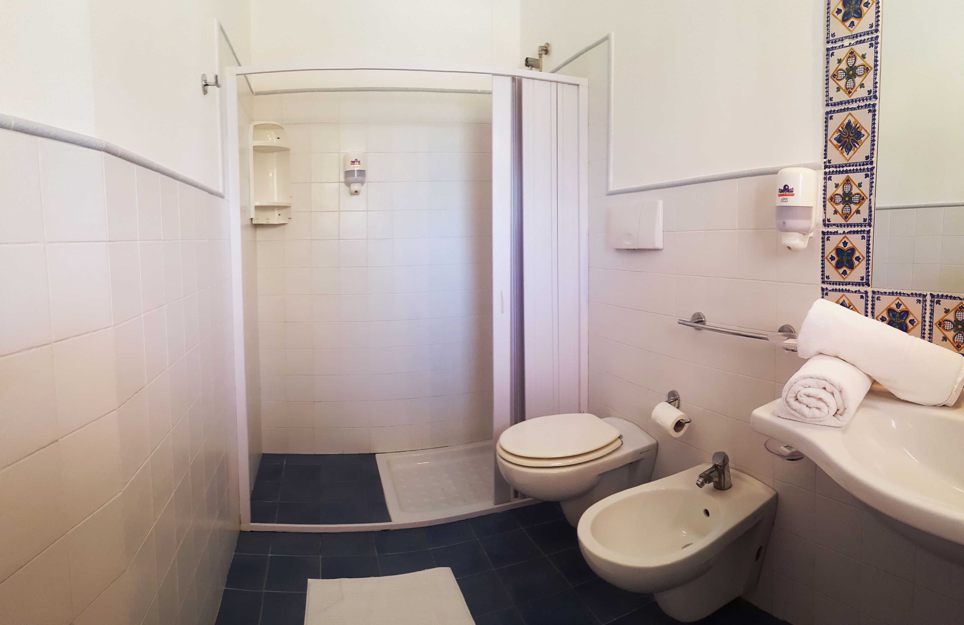 Une salle de bain équipée d’une douche, de toilettes, d’un bidet et d’un lavabo.