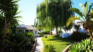 Un jardín con un sendero que conduce a un edificio blanco de techo a lajas.