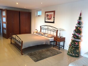 A bedroom with a bed, bedside table, lamp, and a Christmas tree. - Ferienhaus Piešťany (Banka)