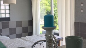 A room with a bed, a window with curtains, a table with a candle, and two mugs. - Ferienhaus Piešťany (Banka)
