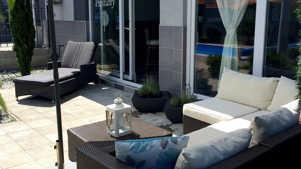An outdoor seating area with wicker furniture, a white umbrella, and a sign for 'Fernhaus Restaurant'. - Ferienhaus Piešťany (Banka)