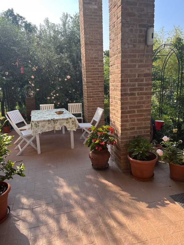 An outdoor patio with a table and chairs, surrounded by brick pillars and potted plants. - B&B San Giorgio (Traversetolo)