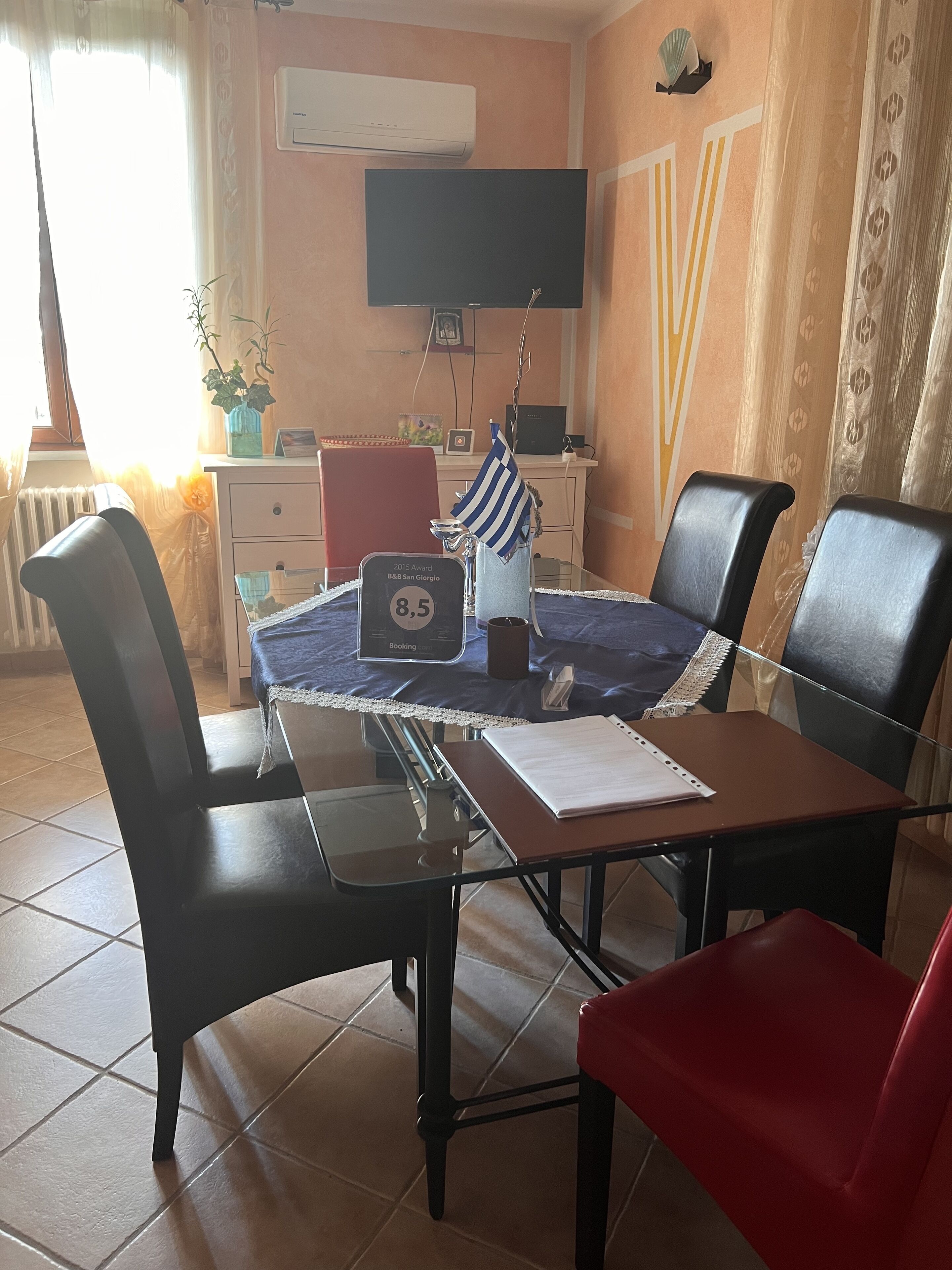 Uma sala de conferência com mesa, cadeiras, uma bandeira, uma televisão e um certificado na parede.
