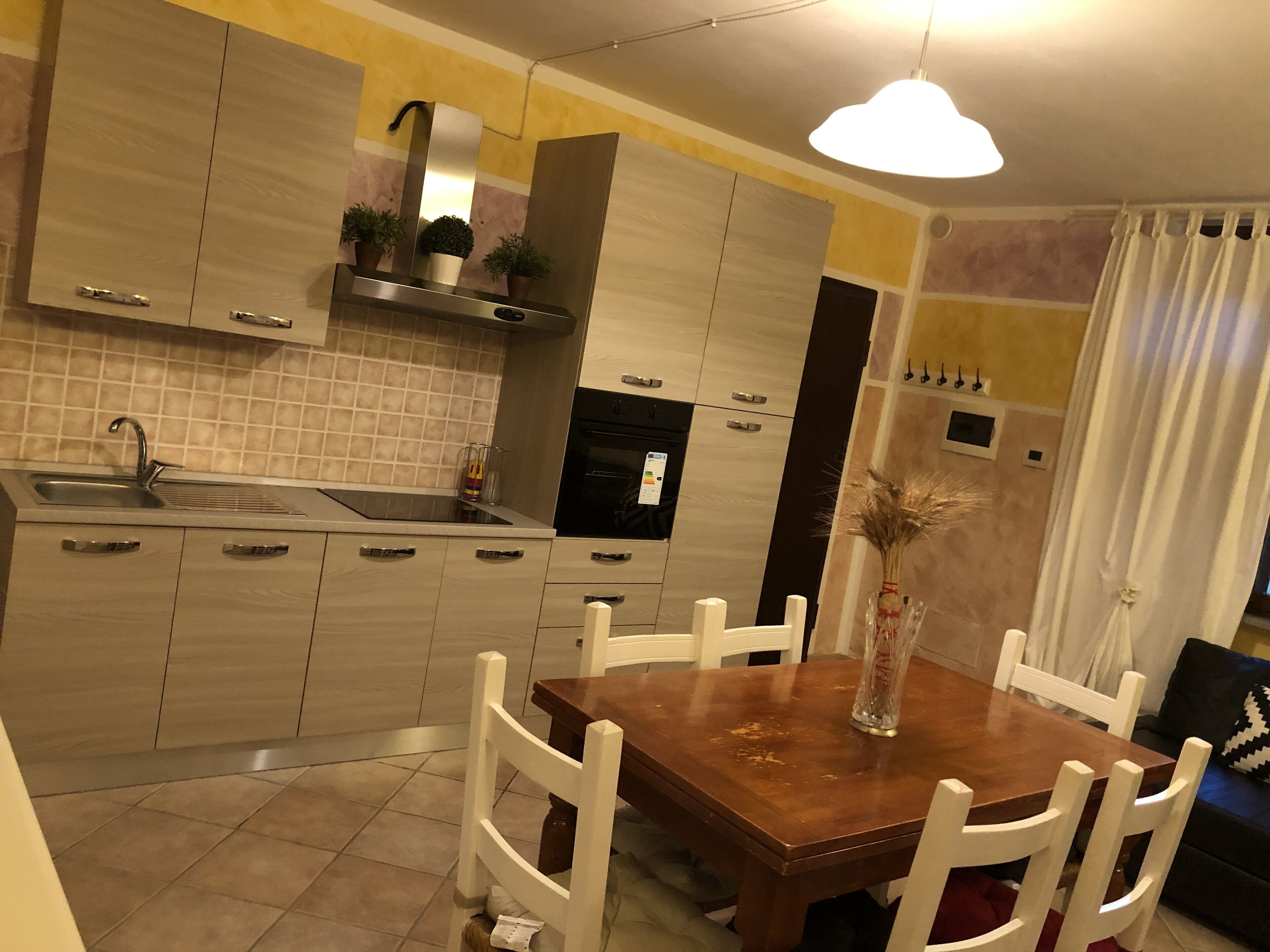 Una cocina moderna con una mesa de madera, sillas blancas y horno empotrado.