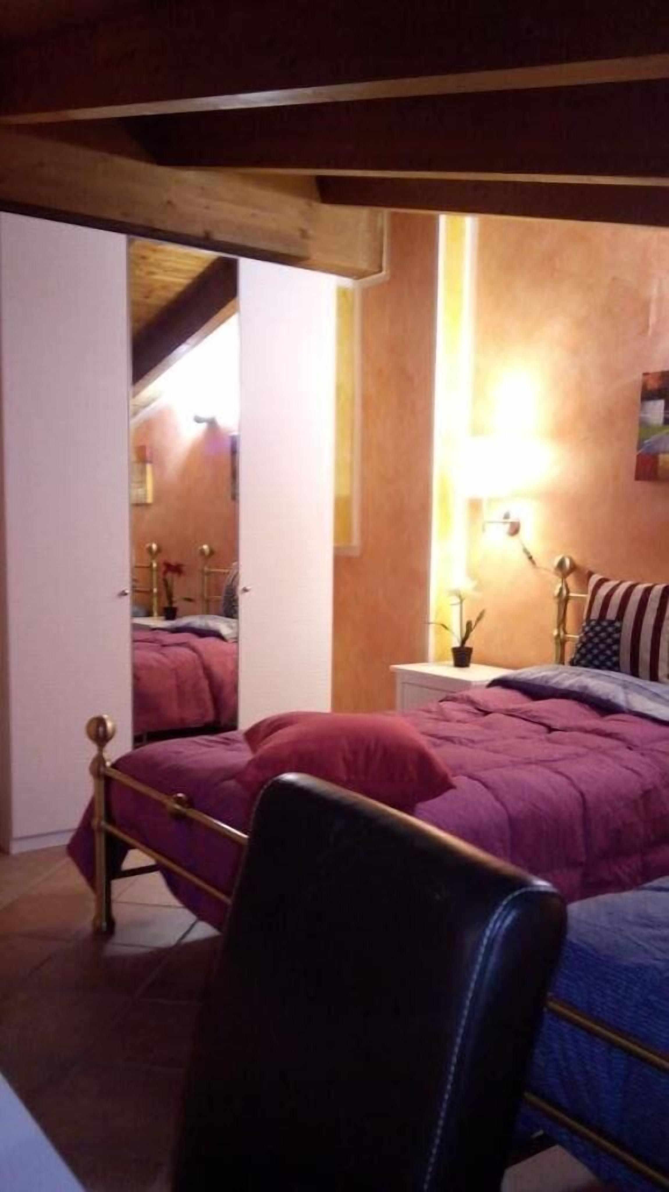 Una camera da letto con un letto, una sedia e un comodino con una lampada.