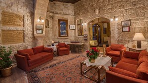 Una habitación acogedora con paredes de piedra, techo de madera y un sofá rojo. Hay cuadros enmarcados en las paredes y una mesita con un jarrón de flores.