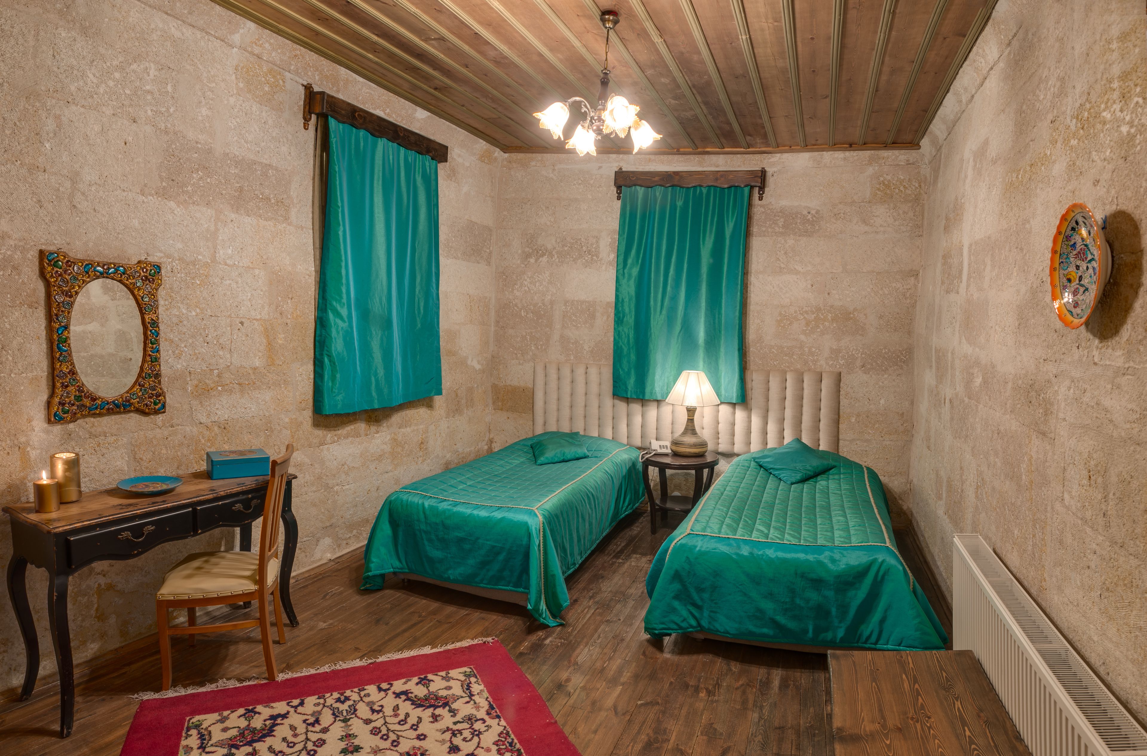 Una habitación con dos camas, un escritorio, una silla, un espejo y un radiador.