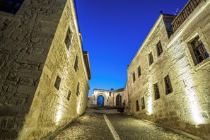 A narrow cobblestone street flanked by historic stone buildings with arched doorways and windows. - Temenni Evi Cave Hotel (Ürgüp)