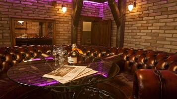 A round glass table with a bottle of Pirae wine, glasses, and menus in a leather booth seating area with brick walls and wooden beams.