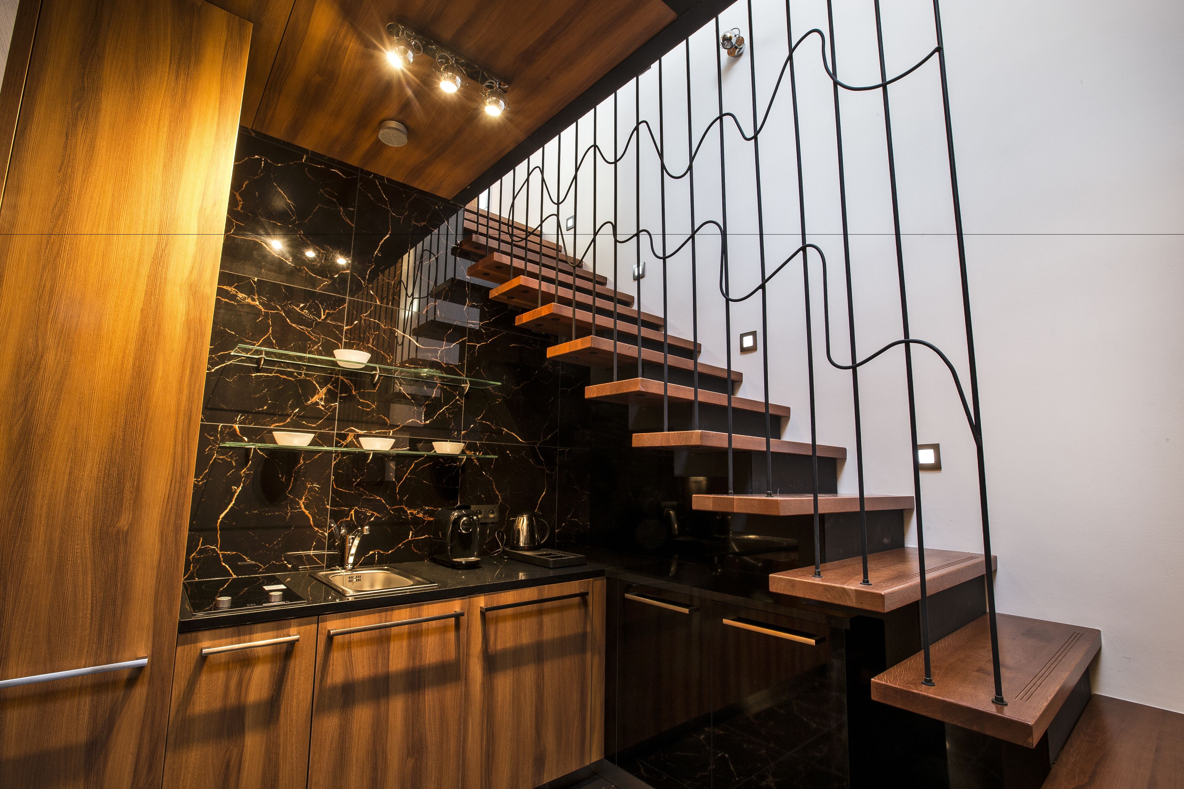 Una cocina moderna con salpicadero de mármol, armarios de madera y un diseño de escalera original.