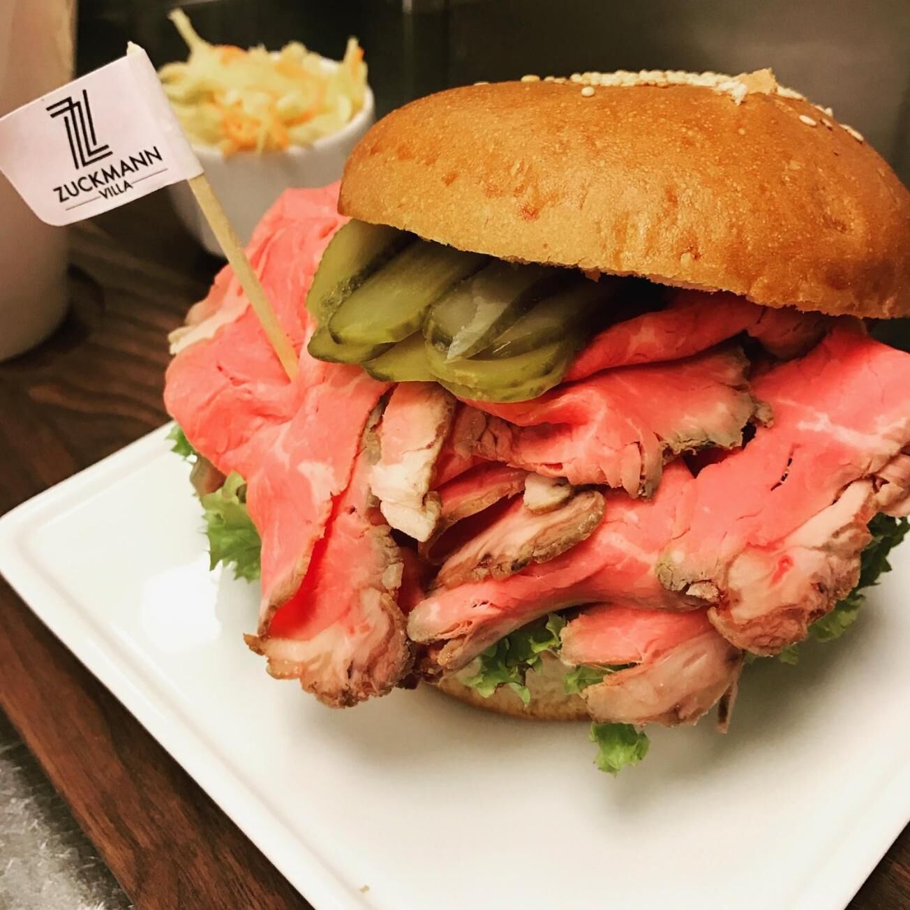 A sandwich with a bun, pickles, and lettuce.