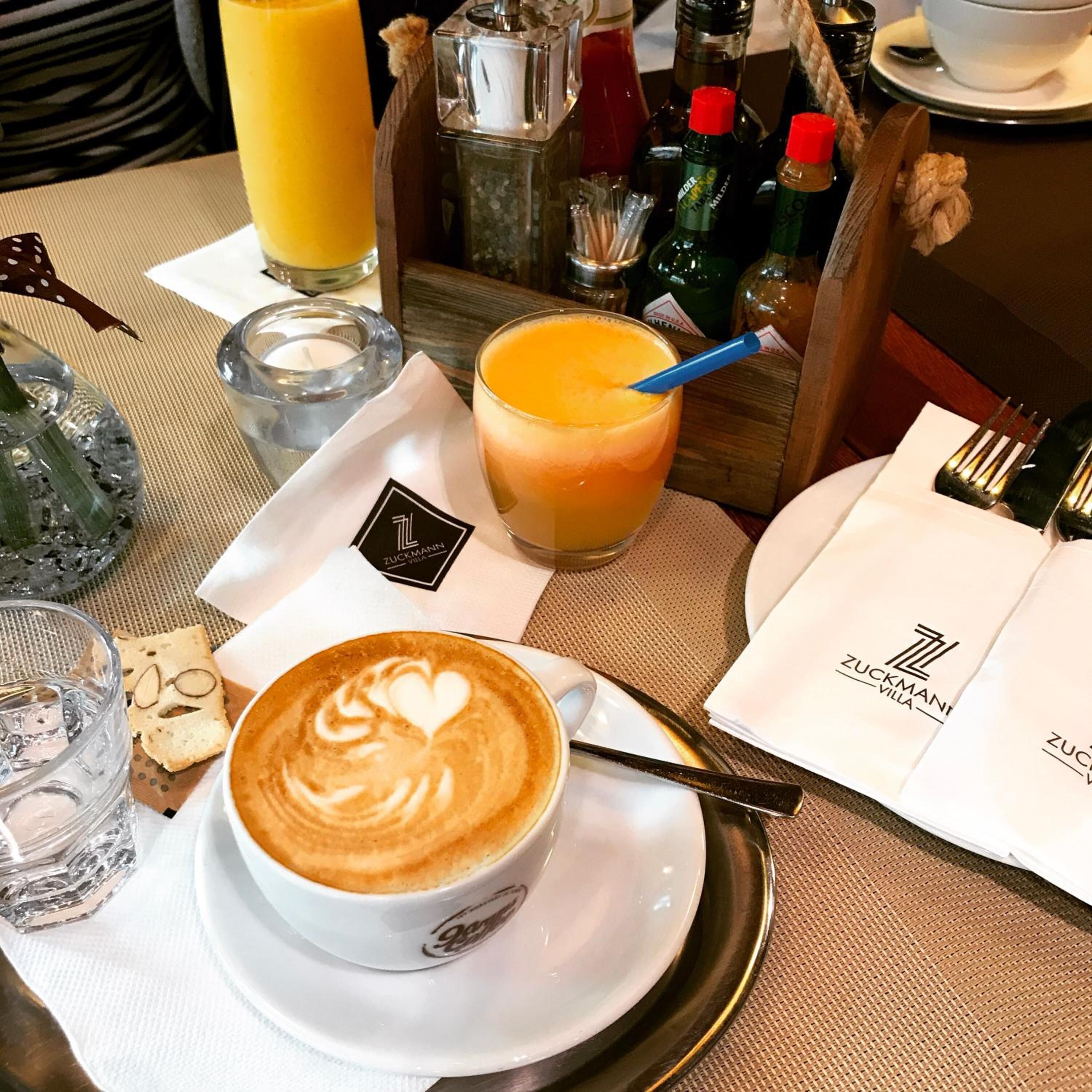 Una mesa dispuesta con una taza de café, un vaso de jugo de naranja, una botella de agua y un menú.
