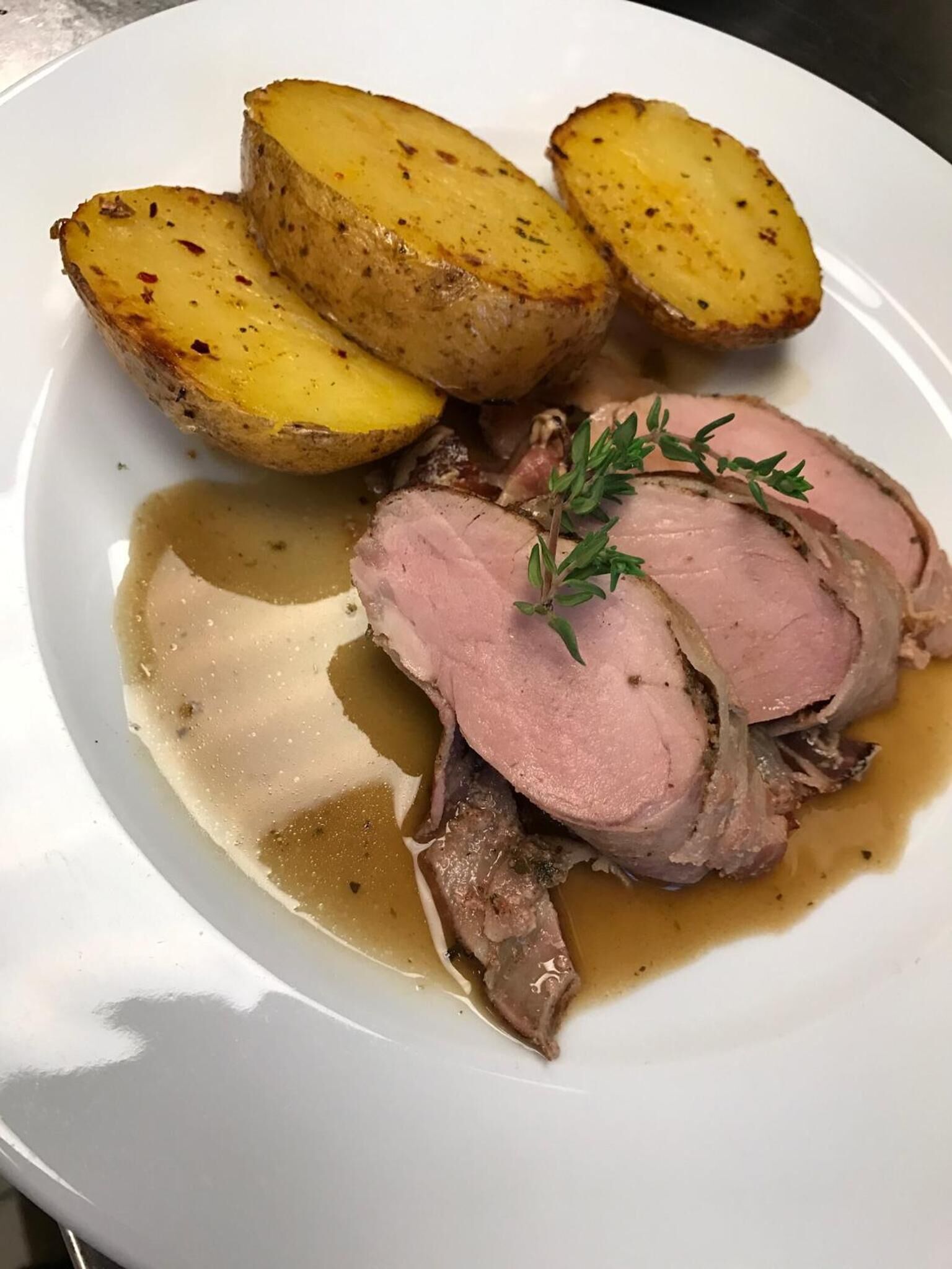 Ein Teller mit geschnittenem Braten, Bratkartoffeln und Soße.