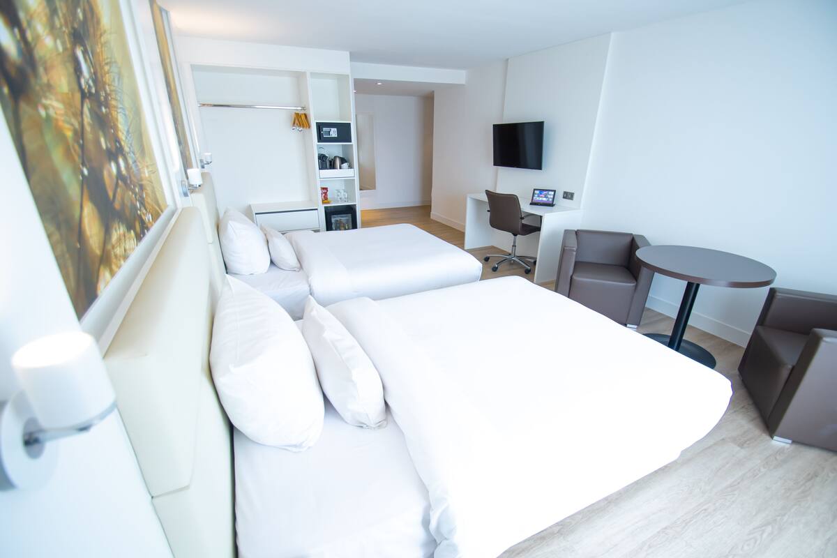 Ein Hotelzimmer mit einem großen Bett, einem Schreibtisch, einem Stuhl, einem kleinen Tisch und einem Fernseher.
