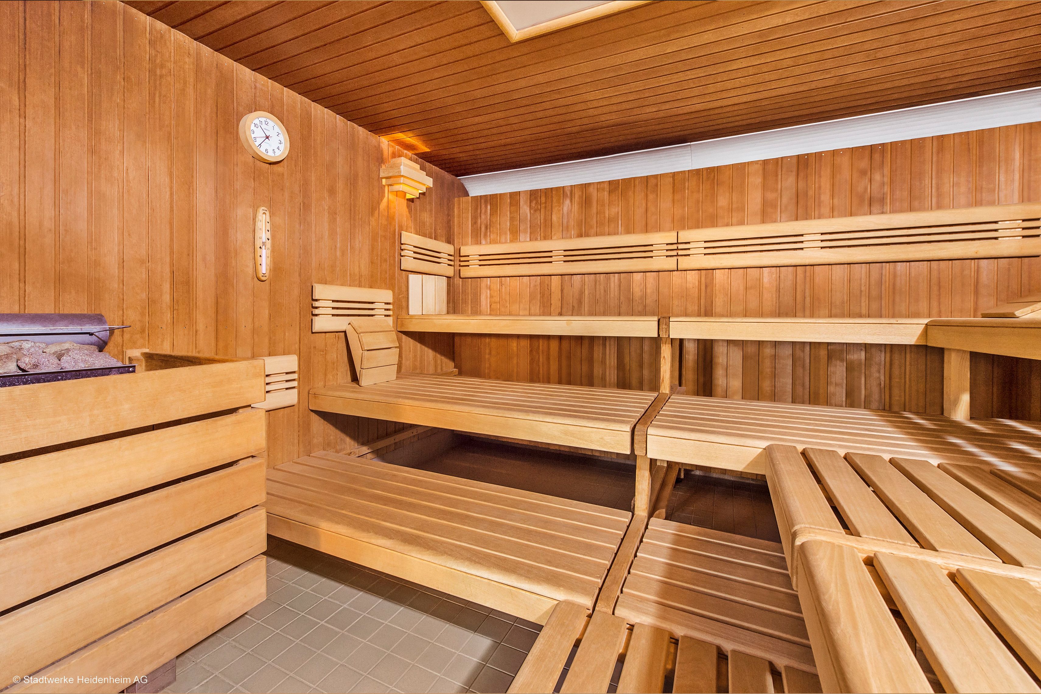 A sauna with wooden benches and a clock on the wall.
