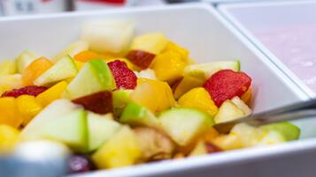 A bowl of mixed fruit salad with various fruits and a spoon.