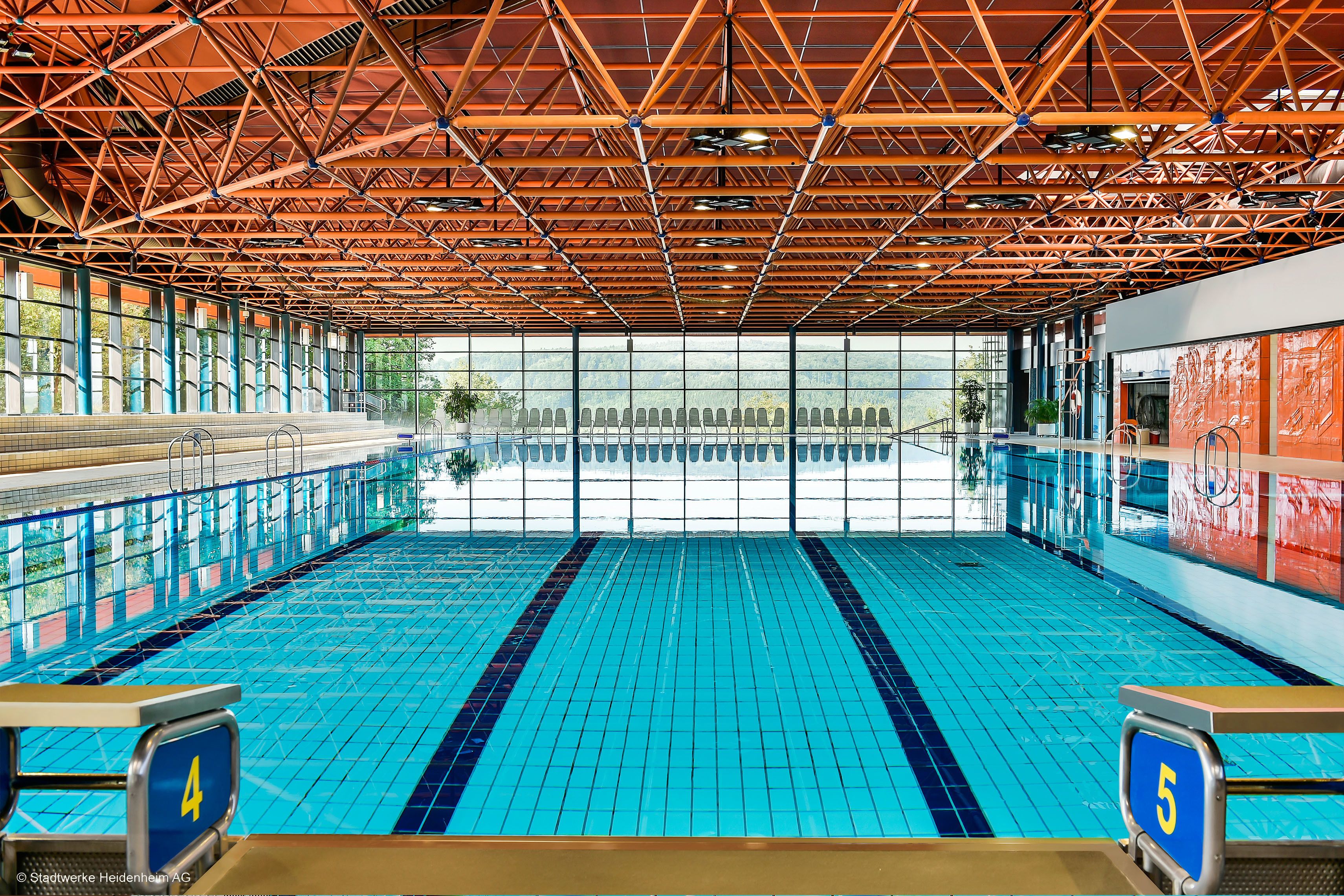 Ein Hallenbad mit hoher Decke und großen Fenstern.