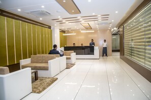Un área de recepción moderna con mostrador, asientos y un panel de vidrio.