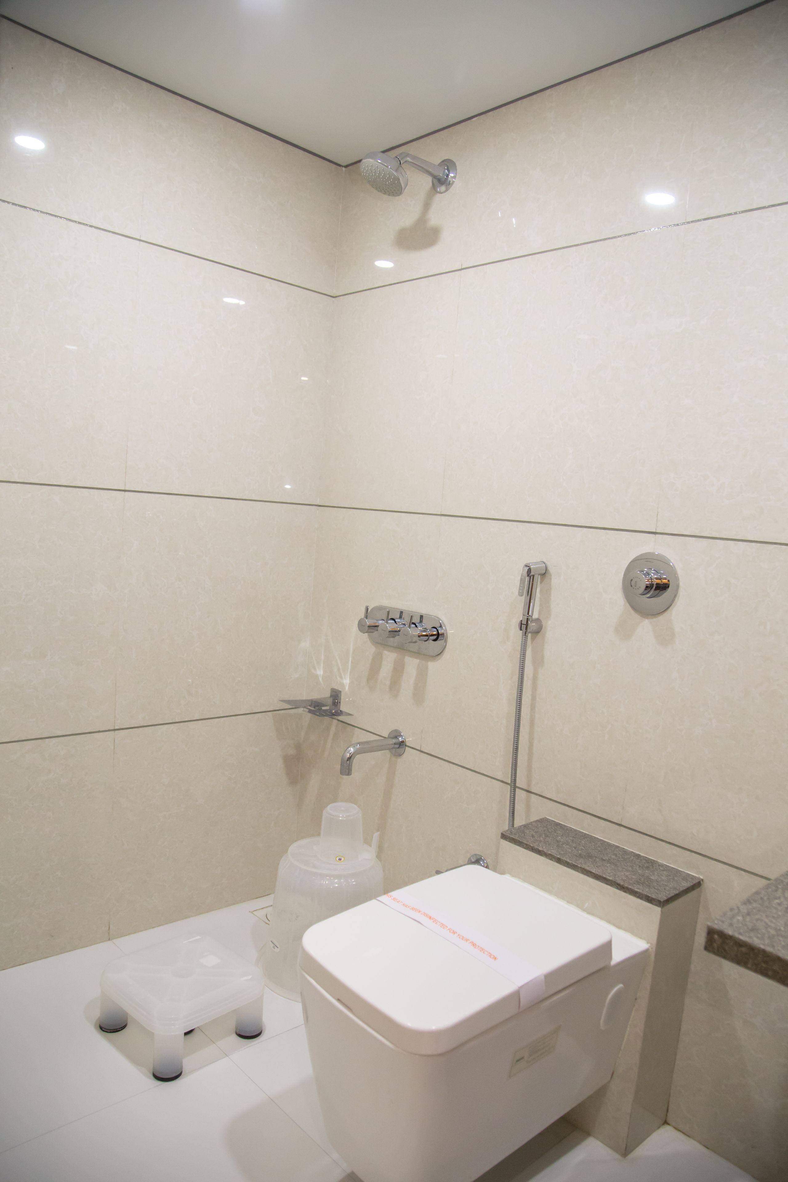 A small, modern bathroom with a toilet, shower, and a step stool.