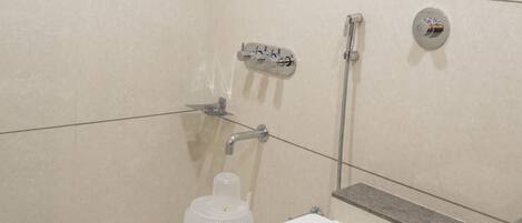 A small, modern bathroom with a toilet, shower, and a step stool.