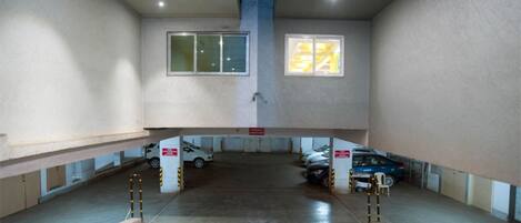Un estacionamiento interior con paredes de concreto, un pilar central y una rampa que conduce a un nivel inferior.