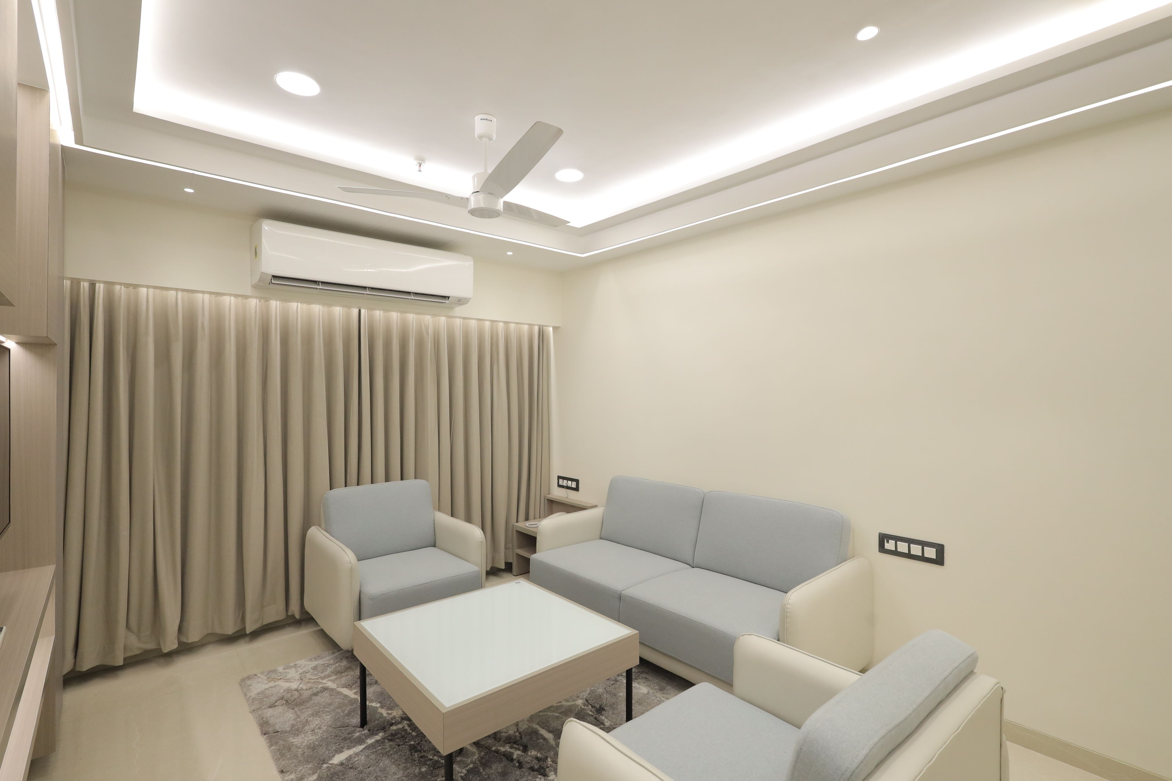 Una sala de estar moderna con un sofá, dos sillones, una mesa de centro y un equipo de aire acondicionado.