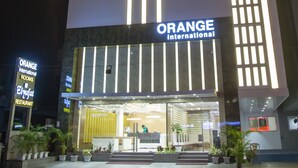 A modern hotel with a prominent 'ORANGE International' sign, a reception area, and a well-lit facade. - Hotel Orange International (Surat)