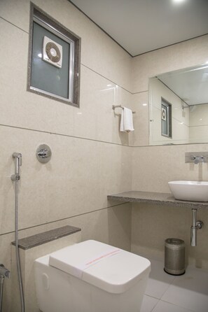 Un baño moderno con inodoro, lavamanos, ducha y un perchero para toallas.