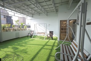 An indoor space with artificial grass, a swing set, and seating areas. - Hotel Orange International (Surat)
