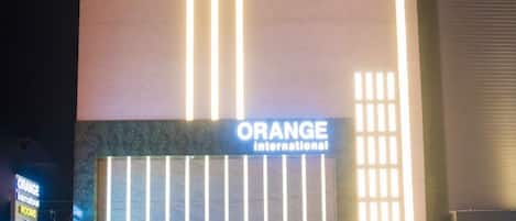 A hotel named 'Orange International' with a modern facade, large windows, and a visible entrance area.
