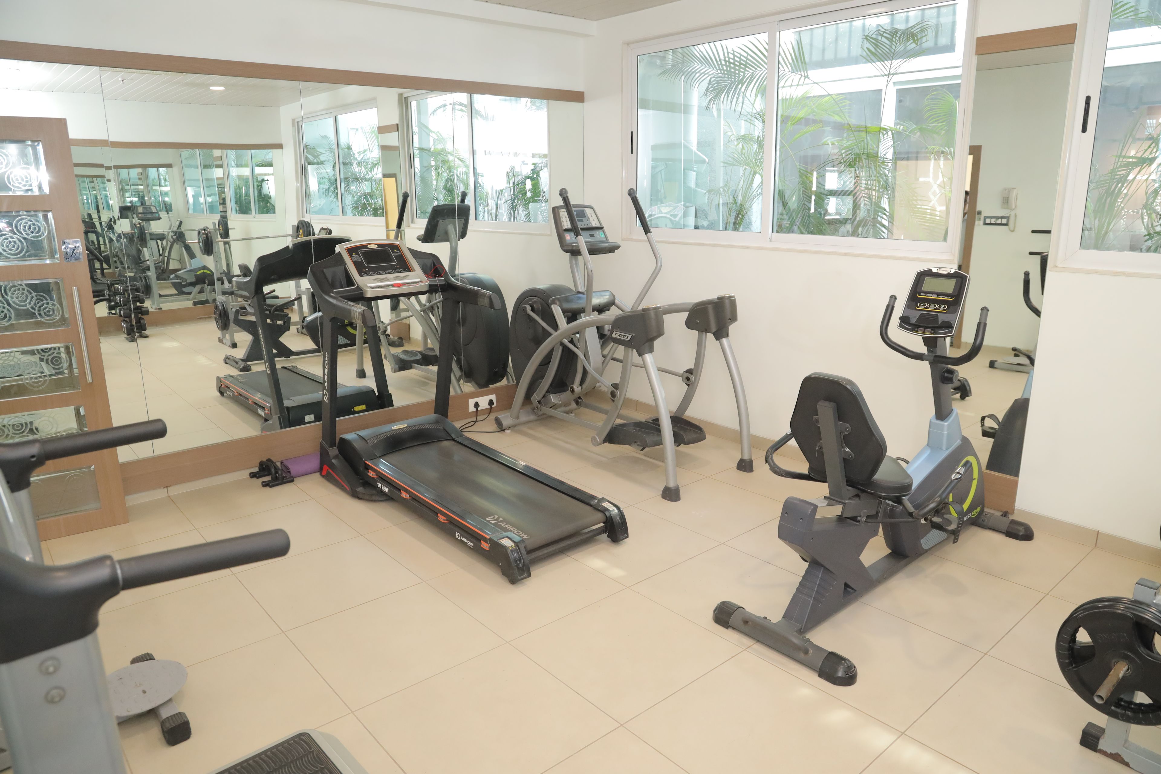 A gym with various exercise equipment including treadmills, elliptical machines, and weightlifting stations.