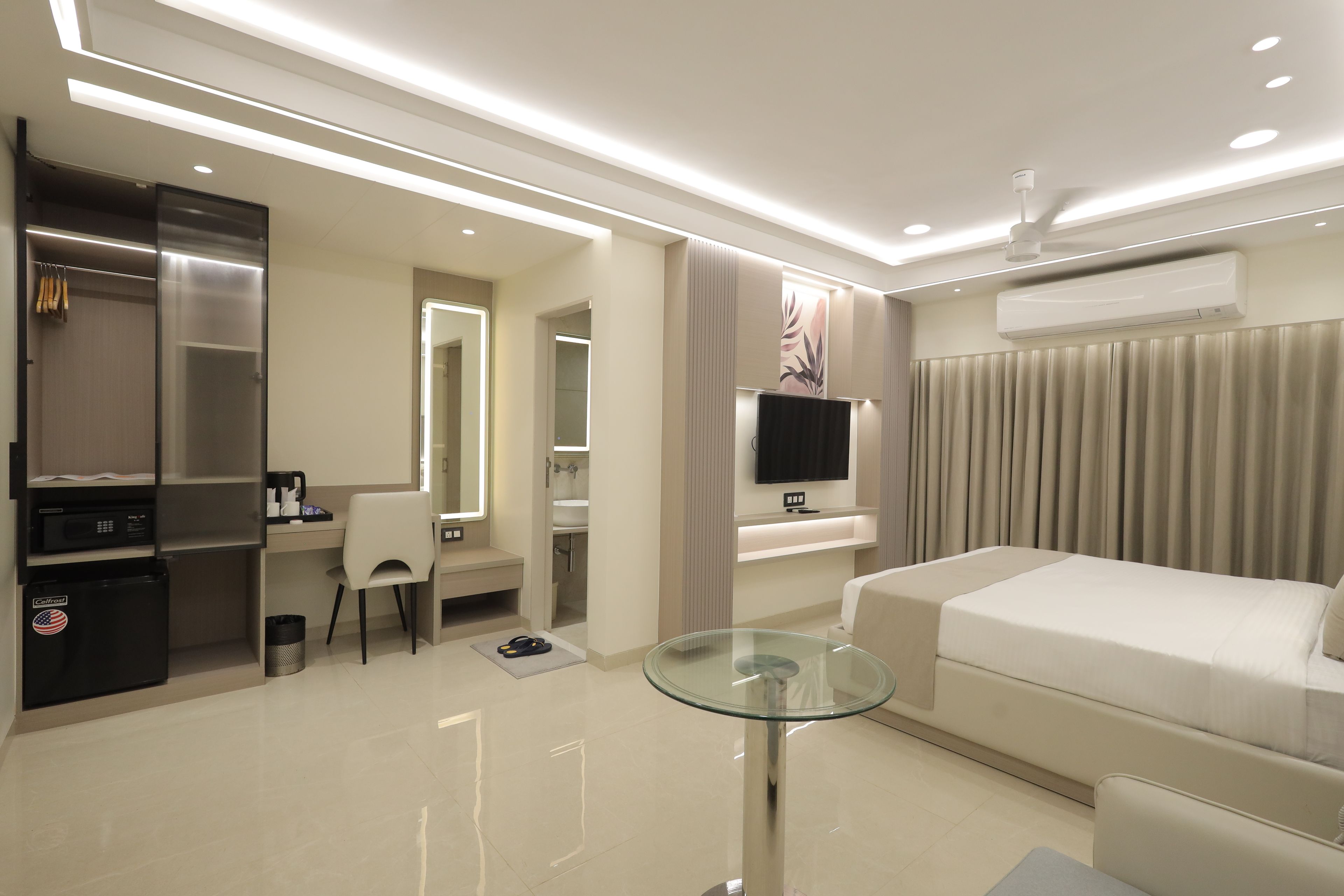 Une chambre d’hôtel équipée d’un lit, d’un bureau avec une chaise, d’une télévision et d’un mini-bar.