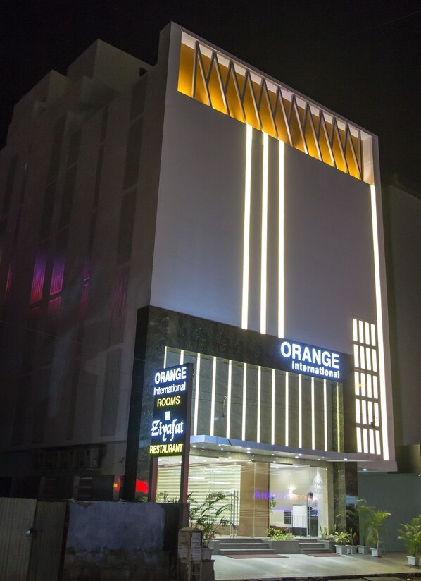 Un edificio con letreros que indican 'Orange International Rooms' y 'Ziyafat Restaurant'.