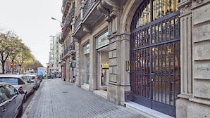 A cobblestone street lined with parked cars and historic buildings with ornate iron gates. - MSB Rambla Catalunya Center (Barcelona)