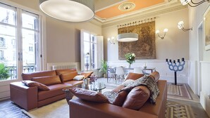 A modern living room with leather sofas, a glass coffee table, and a dining area with a chandelier. - MSB Rambla Catalunya Center (Barcelona)