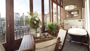 A room with large windows, a bathtub, a wooden table, and a wicker tray with cups. - MSB Rambla Catalunya Center (Barcelona)