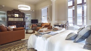 A spacious bedroom with a large bed, a sitting area with a sofa and armchairs, a wooden cabinet, and a large window providing natural light. - MSB Rambla Catalunya Center (Barcelona)
