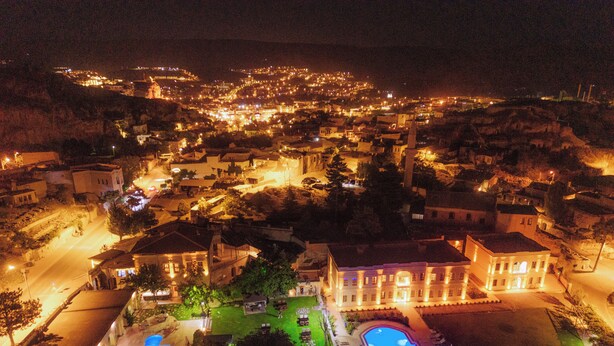 A large building with a swimming pool, surrounded by a well-maintained lawn and a few trees. - Melis Cave Hotel (Ürgüp)