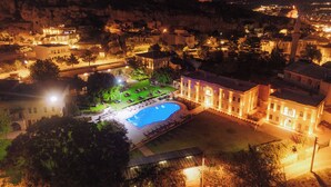 A large building with a swimming pool, surrounded by trees and a small garden. - Melis Cave Hotel (Ürgüp)