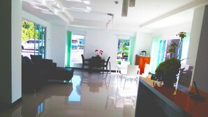 Un moderno vestíbulo de hotel con mostrador de recepción, zona de estar y ventanas amplias que ofrecen vistas al exterior.