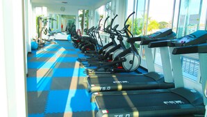 Un gimnasio con varias cintas de correr alineadas frente a una pared con ventanas amplias, que dejan entrar luz natural.