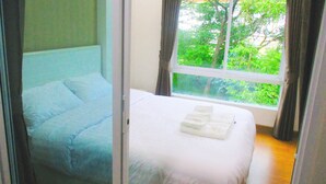 Un dormitorio con cama, ventana y vista a zonas verdes.