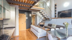A modern interior with a kitchen, dining area, and a staircase leading to an upper level.
