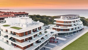 A modern multi-story building with a rooftop terrace and a circular structure with a glass facade. - VacationClub - Baltic Park Molo Apartments (Swinoujscie)