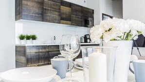 A modern kitchen with a white countertop, a vase of white flowers, a lit candle, and a glass pitcher. - VacationClub - Baltic Park Molo Apartments (Swinoujscie)